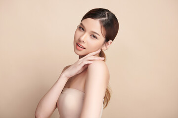 Obraz premium A beautiful young Asian woman with clean, fresh skin against a beige background. Skincare, facial treatment, cosmetology, beauty, and spa. An elegant portrait of an Asian woman.
