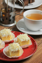 a red plate of sliced chiffon with cheese on top and a cup of tea