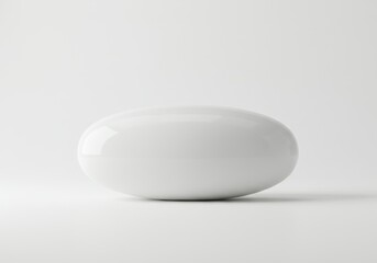 A minimalist image of a single white oval object on a white surface with soft lighting and shadow detail
