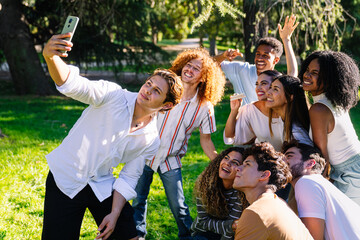 Group of cheerful multi ethnic students taking a selfie with a smartphone in a park during a break
