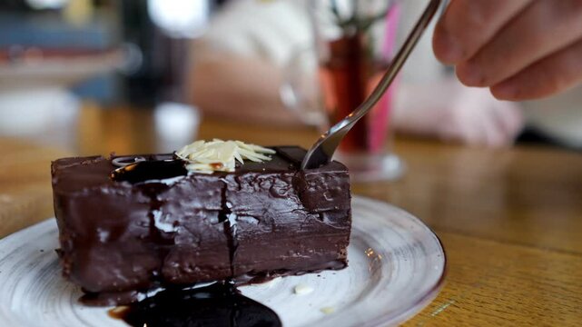 Person cuts into chocolate cake with fork enjoying meal