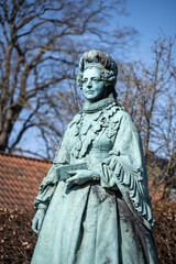 Obraz premium The statue of Queen Caroline Amalie stands proudly in Rosenborg Castle Garden, surrounded by trees under a clear blue sky, reflecting the historical significance of Copenhagen, Denmark.