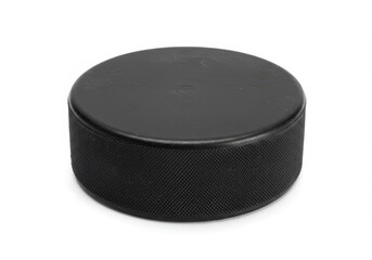 A close up studio shot of a single black hockey puck isolated on a white background with soft shadows