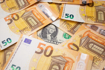 Close up of fifty euro money bills and a dollar bill in the middle background