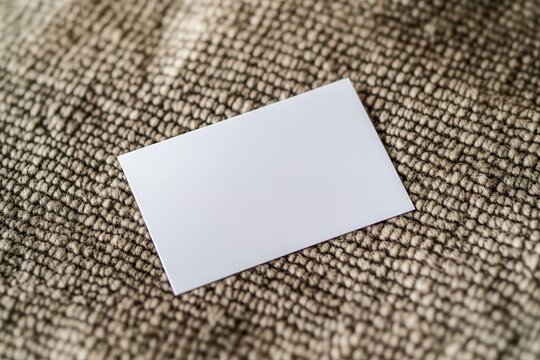 Blank white business card lying on a textured surface, ideal for branding or design mockups