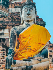 Close-up view of large Buddha statue draped in yellow robes in Ayutthaya, Thailand.