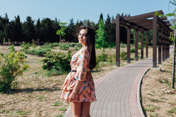 Brunette in a summer dress with flowers walking