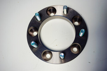A single silver-colored wheel spacer with multiple bolt holes and attached studs is shown on a...