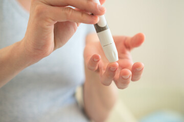 Future mother performing important glucose test during pregnancy. Close-up of finger prick blood...