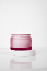 magenta skincare jar packaging with the lid open on white background