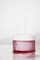 magenta skincare jar packaging with the water from above on white background