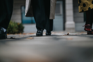 A close-up perspective of the shoes and legs of individuals walking on a paved walkway near an urban building, symbolizing progress, teamwork, and a collaborative work environment.