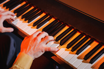 Musician playing piano keys in a dimly lit setting during an evening performance
