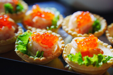 Gourmet shrimp tartlets with leafy greens and bright caviar topping
