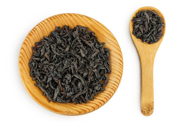 Dry black tea leaves in wooden bowl and spoon isolated on white background. Top view. Flat lay