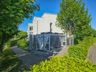 external unit of an air source heat pump in front of a modern low energy multi family house...