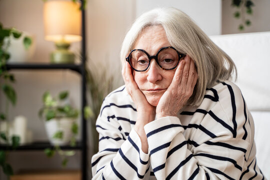 Thoughtful woman with white sitting with head in hands looking despaired