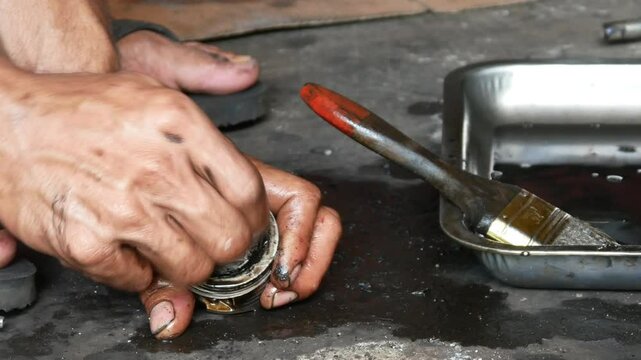 A motorcycle mechanic performs repairs and maintenance, cleaning on motorcycle pistons.