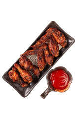 Grilled chicken wings on black plate. Served with chili sauce. Isolated picture perfect for advertising or commercial use