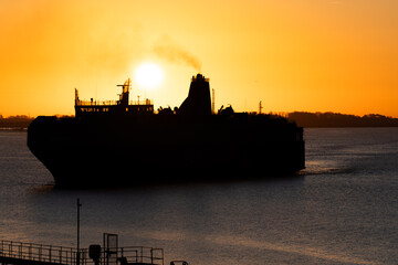Silhouette of transport ferry arriving at docks at sunrise