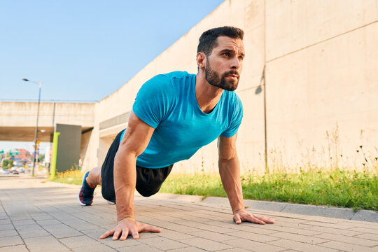Sporty man doing pushups exercise in a city during street workout