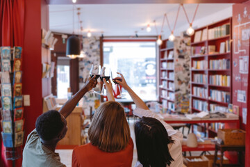 Friends toasting with red wine in bookstore: celebrating literature and friendship