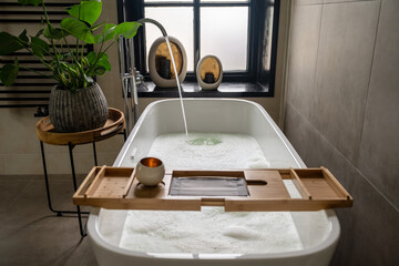 Interior of bathroom with bathtub, dressing table, shelving and large window