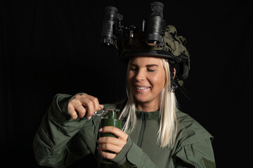 Confident female soldier in tactical gear with night vision goggles preparing a hand grenade, ready for mission and defense.