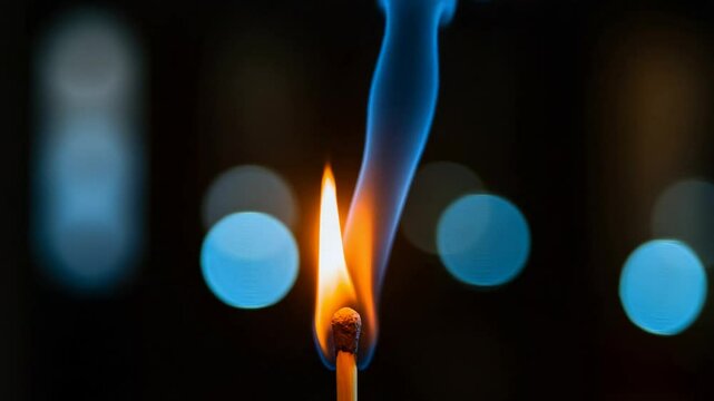 Burning matchstick with flame and smoke against a dark background