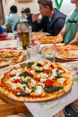 Friends and family sit around a table enjoying pizza together