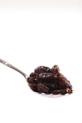 a spoon of dried raisin isolated on white background