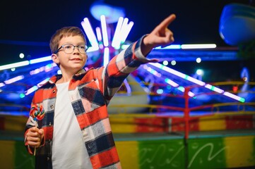A cute boy happily spends time in an amusement park. Concept of happy childhood and holidays.