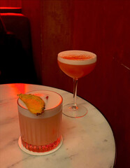 Two fancy cocktails under red lighting