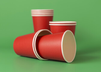 Disposable red paper cups on a green closeup, mockup. No plastic and sustainable Christmas