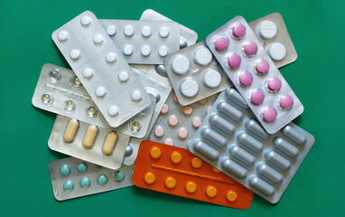 The variety of medical pills on green background.