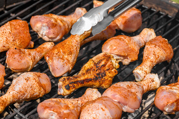 Grill master przewraca pałki z kurczaka na rozgrzanym ruszcie, pikantny kurczak z chrupiącą skórką 