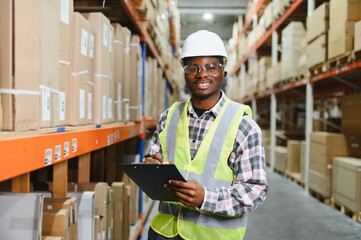 Portrait of african american warehouseman with clipboard checking delivery, stock in warehouse....