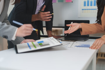 Business professionals engage in a collaborative meeting, analyzing financial reports and discussing strategies. Laptops and charts indicate a focus on data driven decision making