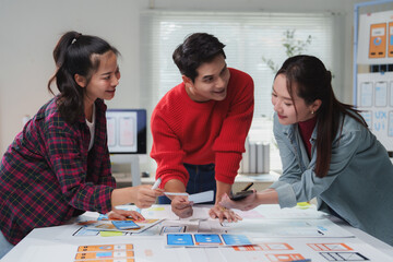 Three asian web designers are discussing user interface and user experience together for mobile...