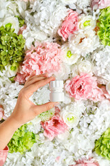 A young woman holds a jar of allergy pills. Medicine and healthcare concept. Background of flowers