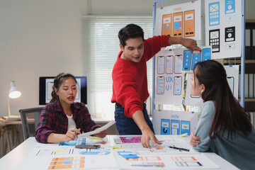 Diverse team of young professionals engaged in a collaborative ux design session. They are...