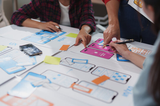 User experience and user interface designers are working together to create a new mobile application, discussing functionalities and design