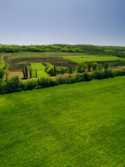 An aerial view showcasing vibrant green fields and expansive farmland, adorned with lush trees, all...