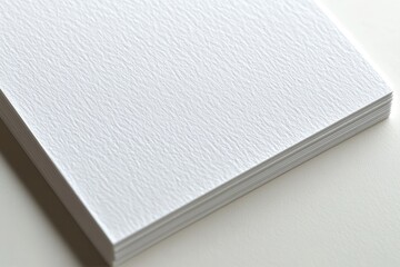Stacked sheets of textured white paper on a smooth surface, ideal for stationery and crafts