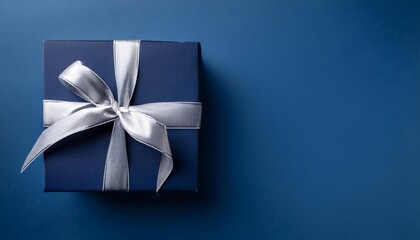Dark Blue Gift Box with Silver Ribbon on Dark Blue Background. Top View of Graduation Gifts with Copy Space
