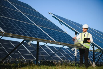 Businessman or engineer standing near solar panels