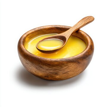 Ghee in a wooden bowl with a wooden spoon on a white background