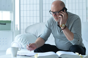  old man with book talking on phone and taking notes