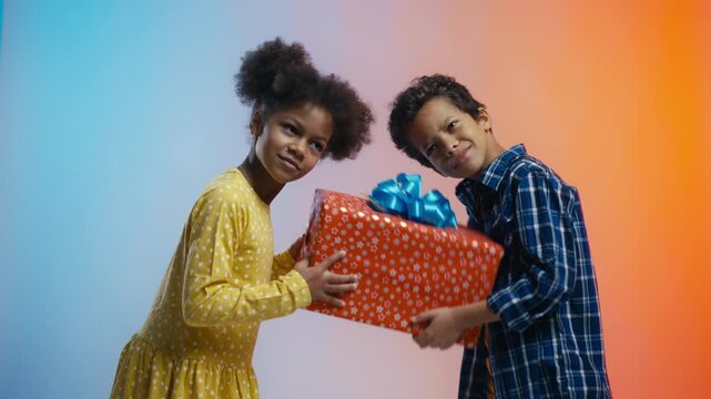 Young girl and boy shaking large present box, guessing gift during holiday fun