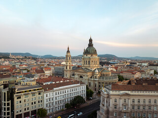 Timeless elegance of Budapest St. Stephen Basilica crowned by soft golden light, intricate city patterns, endless rooftops, and charming squares create stunning aerial portrait. Travel concept